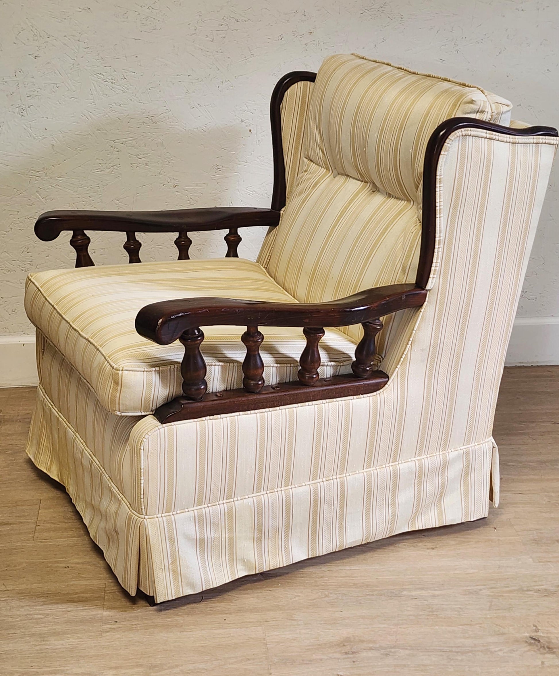 Striped armchair with wooden armrests on a wooden floor.