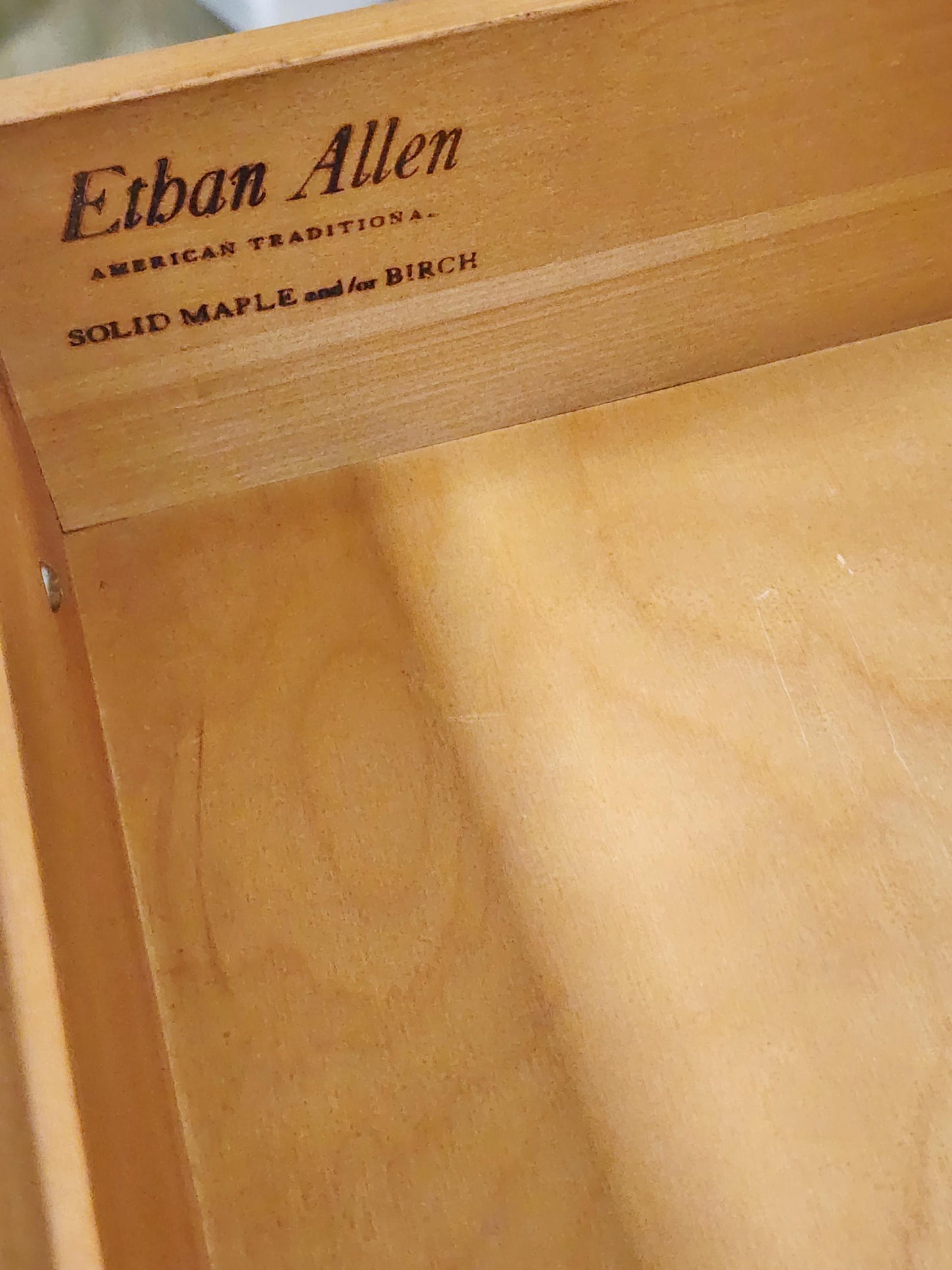 Wooden furniture with 'Ethan Allen' branding on a wooden surface.